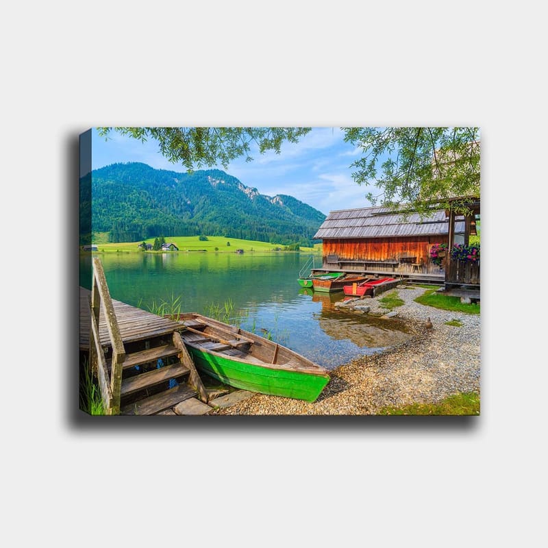 Canvas taulu 70x100 cm - Tyyni järvimaisema värikkäillä veneillä puisella laiturilla ja ympäröivillä vihreillä vuorilla, Vihreä / Sininen / Ruskea