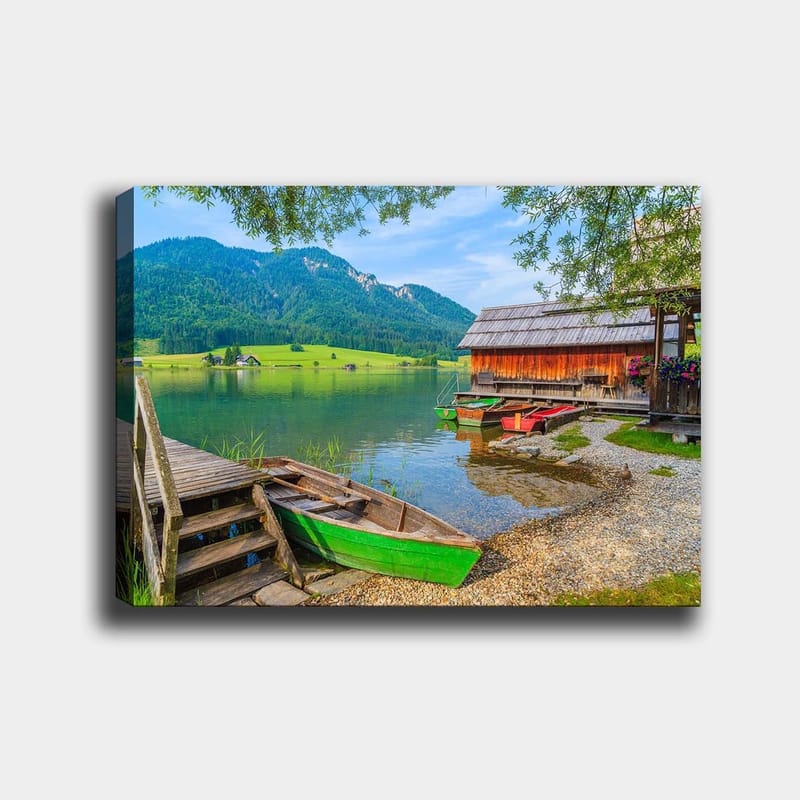 Canvas taulu 70x100 cm - Tyyni järvimaisema värikkäillä veneillä puisella laiturilla ja ympäröivillä vihreillä vuorilla, Vihreä / Sininen / Ruskea