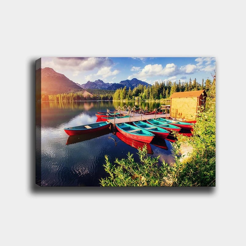 Canvas taulu 70x100 cm - Useita värikkäitä veneitä makaa peilimäisellä järvellä rehevien puiden ja vuorten ympäröimänä, Punainen / Turkoosi / Vihreä
