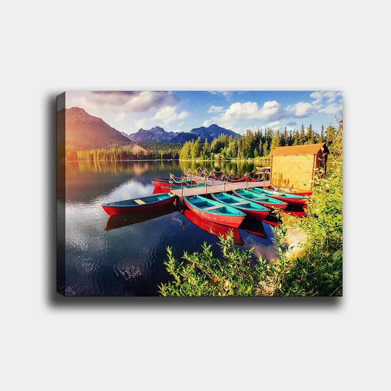 Canvas taulu 70x100 cm - Useita värikkäitä veneitä makaa peilimäisellä järvellä rehevien puiden ja vuorten ympäröimänä, Punainen / Turkoosi / Vihreä