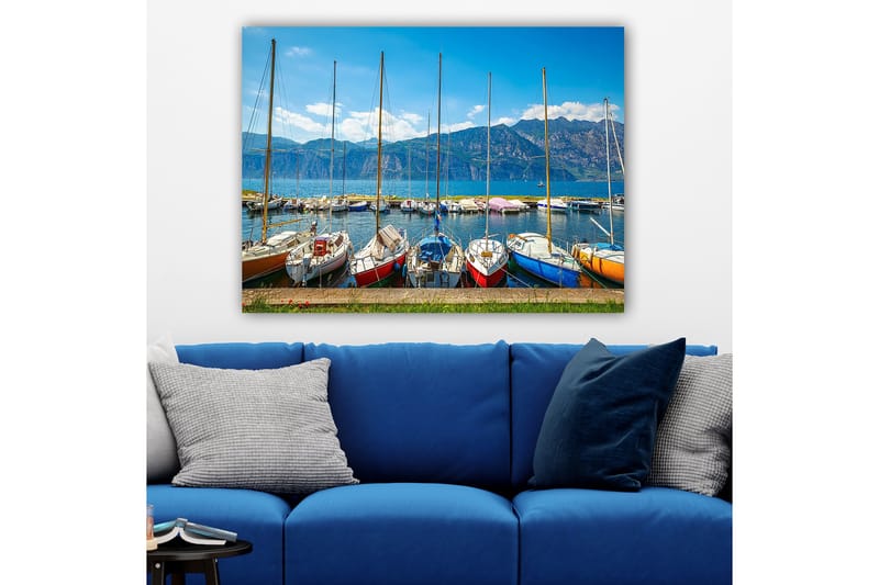 Canvas taulu 70x100 cm - Useita värikkäitä purjeveneitä satamassa, taustalla vuoret, Sininen / Punainen / Oranssi