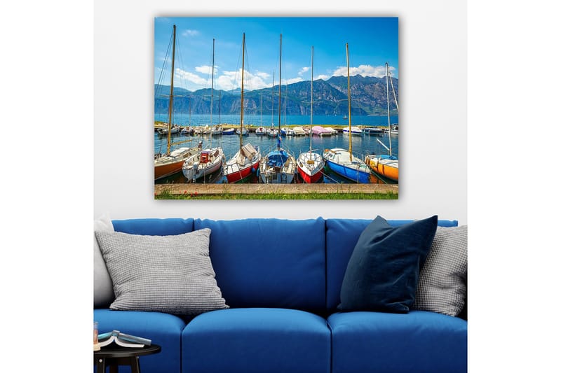 Canvas taulu 70x100 cm - Useita värikkäitä purjeveneitä satamassa, taustalla vuoret, Sininen / Punainen / Oranssi