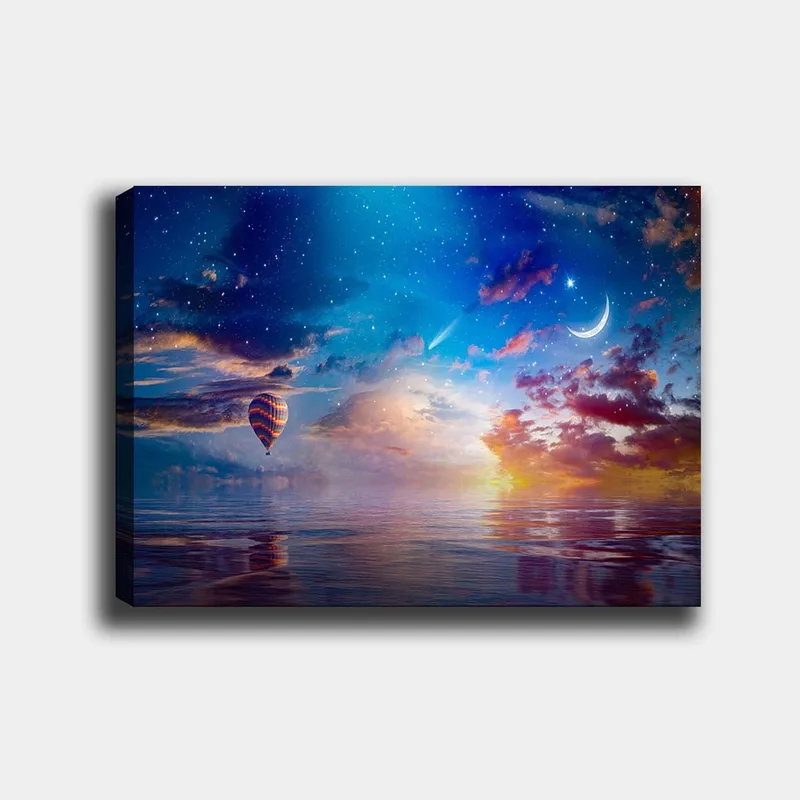 Canvas taulu 70x100 cm - Värikäs kuumailmapallo leijuu peilimäisen pinnan yllä tähtitaivaan alla dramaattisten pilvien ja kuun keskellä, Sininen / Oranssi / Punainen