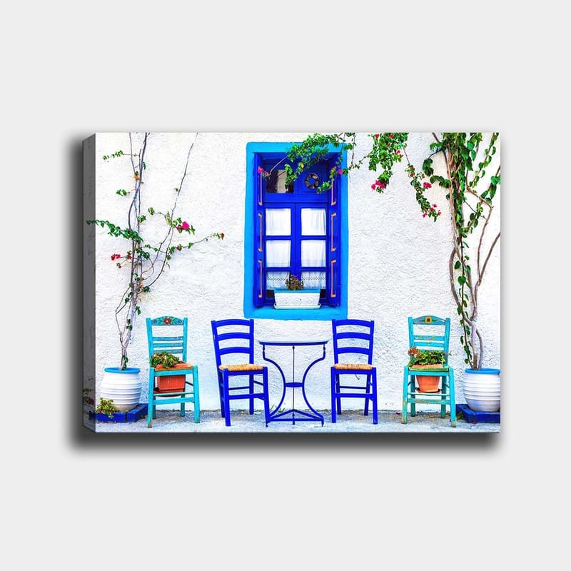 Canvas taulu 70x100 cm - Värikäs ulkoruokailutila sinisillä tuoleilla ja ikkunoilla välimerellisessä ympäristössä, Sininen / Vihreä / Valkoinen