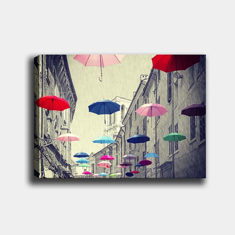 Canvas taulu 70x100 cm - Värikkäät sateenvarjot leijuvat harmaan kaupungin kadun yllä, Punainen / Sininen / Vaaleanpunainen