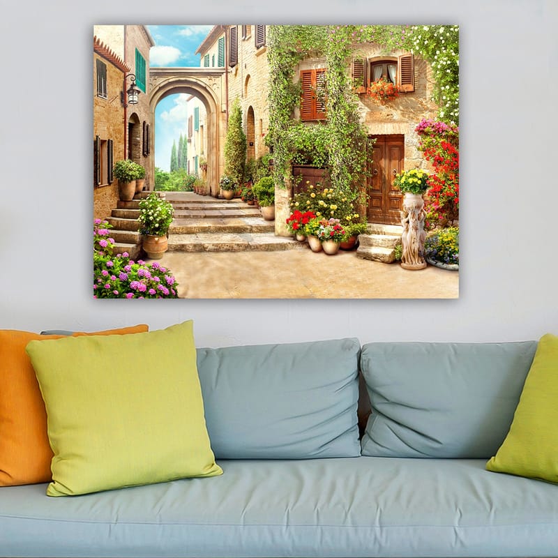 Canvas taulu 70x100 cm - Viehättävä katu kukkien ja vehreyden keskellä viehättävässä kylämäisessä ympäristössä - Vihreä / Keltainen / Vaaleanpunainen - Sisustustuotteet - Taulu & taide - Canvas-taulu