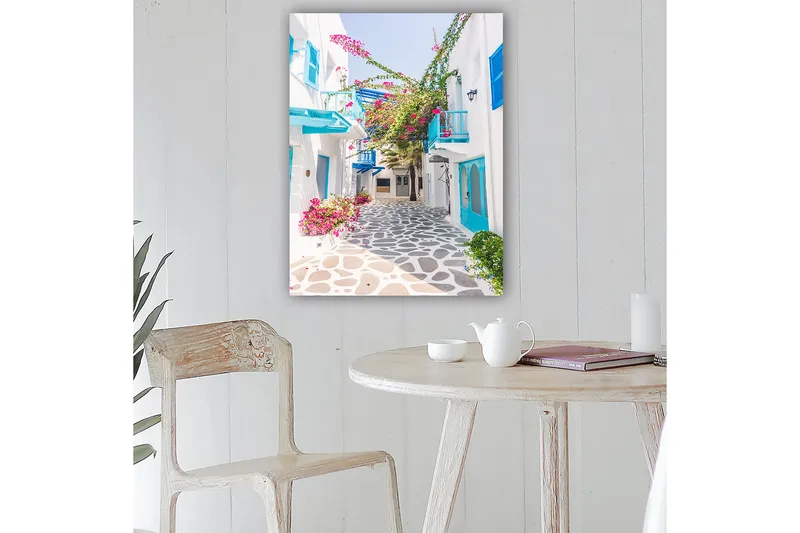 Canvas taulu 70x100 cm - Viehättävä kuja, jossa on valkoisia taloja ja värikkäitä kukkia välimerellisessä ympäristössä - Sininen / Vaaleanpunainen / Valkoinen - Sisustustuotteet - Taulu & taide - Canvas-taulu