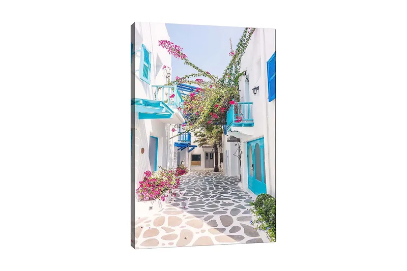 Canvas taulu 70x100 cm - Viehättävä kuja, jossa on valkoisia taloja ja värikkäitä kukkia välimerellisessä ympäristössä, Sininen / Vaaleanpunainen / Valkoinen