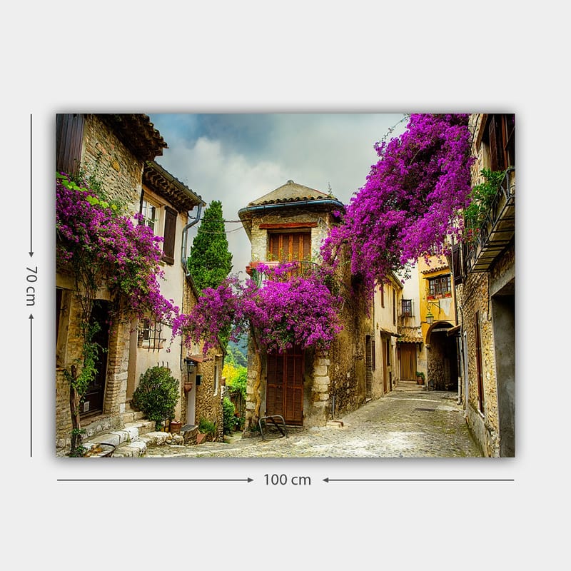 Canvas taulu 70x100 cm - Viehättävä kuja, jota ympäröivät värikkäät kukat viehättävässä kylämiljöössä - Violetti / Vihreä / Beige - Sisustustuotteet - Taulu & taide - Canvas-taulu