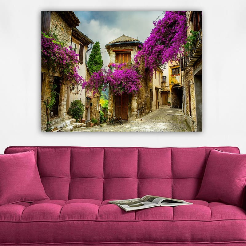 Canvas taulu 70x100 cm - Viehättävä kuja, jota ympäröivät värikkäät kukat viehättävässä kylämiljöössä - Violetti / Vihreä / Beige - Sisustustuotteet - Taulu & taide - Canvas-taulu