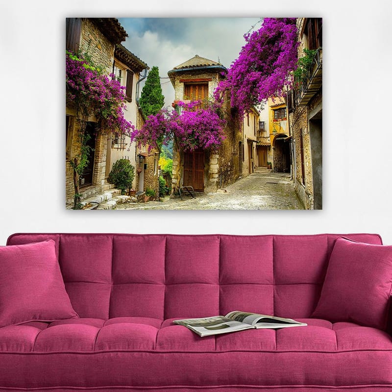 Canvas taulu 70x100 cm - Viehättävä kuja, jota ympäröivät värikkäät kukat viehättävässä kylämiljöössä - Violetti / Vihreä / Beige - Sisustustuotteet - Taulu & taide - Canvas-taulu