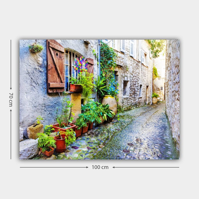 Canvas taulu 70x100 cm - Viehättävä kuja kivitaloineen ja kukkaruukkuineen luo eloisan tunnelman - Vihreä / Sininen / Beige - Sisustustuotteet - Taulu & taide - Canvas-taulu