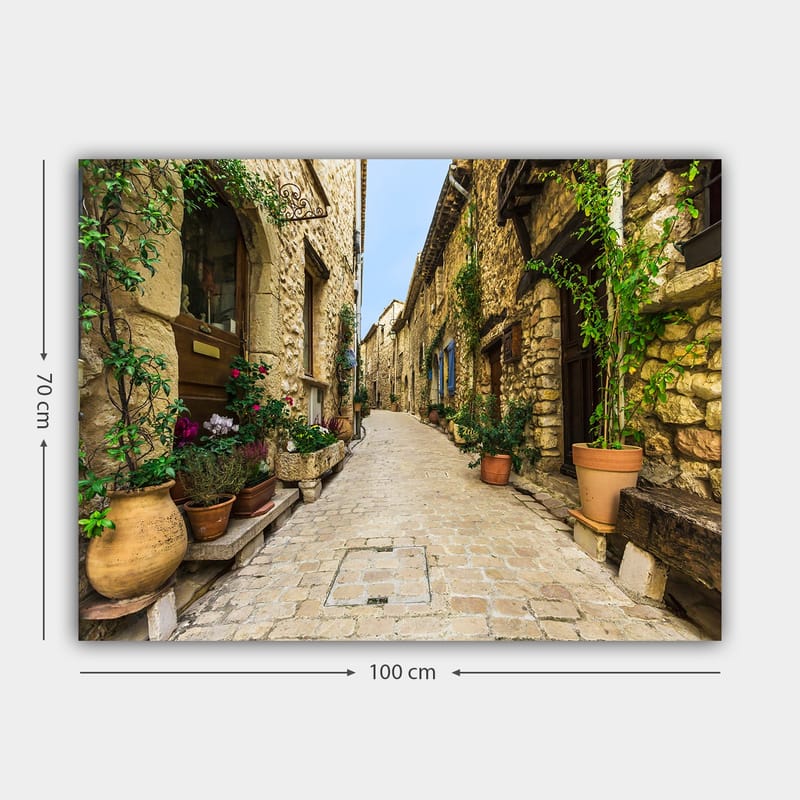 Canvas taulu 70x100 cm - Viehättävä kuja vanhassa kylässä kivitalojen ja kukkaruukkujen ympäröimänä - Beige / Vihreä / Terrakotta - Sisustustuotteet - Taulu & taide - Canvas-taulu