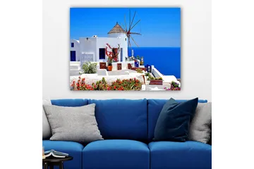 Canvas taulu 70x100 cm - Viehättävä näkymä valkoiseksi kalkitusta rakennuksesta, jossa on perinteinen tuulimylly ja värikkäitä kukkia Santorinilla - Valkoinen / Sininen / Punainen - Sisustustuotteet - Taulu & taide - Canvas-taulu