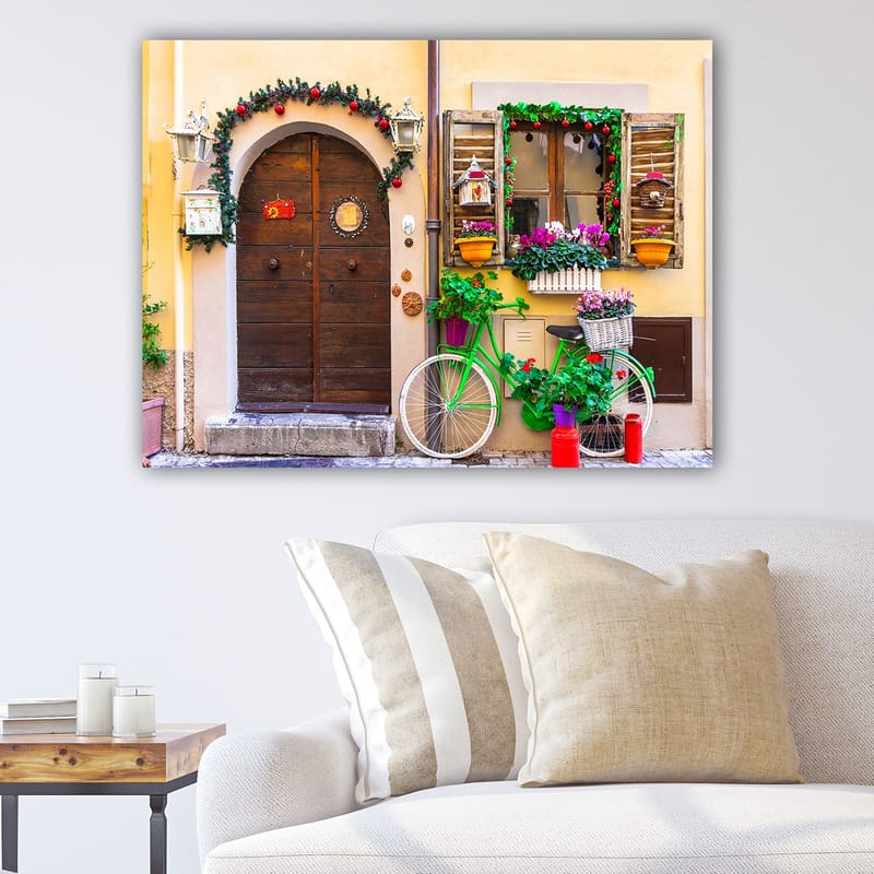 Canvas taulu 70x100 cm - Viehättävä ovi kukilla ja polkupyörällä värikkäässä ympäristössä, Vihreä / Ruskea / Punainen