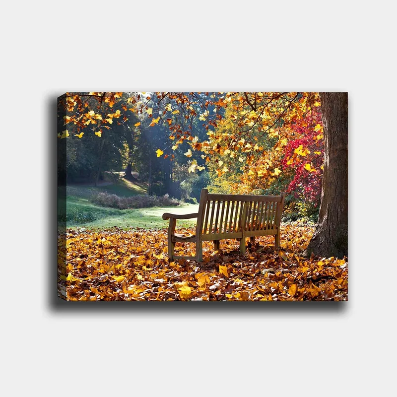 Canvas taulu 70x100 cm - Penkki värikkäiden syksynlehtien ympäröimänä luonnonkauniissa ympäristössä, Oranssi / Keltainen / Punainen