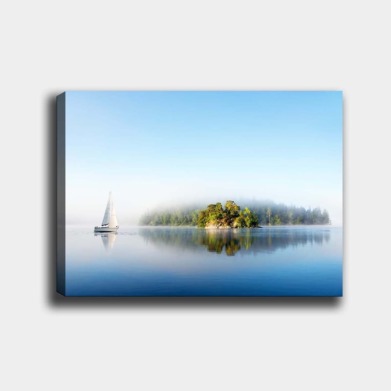 Canvas taulu 70x100 cm - Purjevene liukuu peilimäisen järven yli sumuisen saaren taustalla, Sininen / Vihreä / Valkoinen