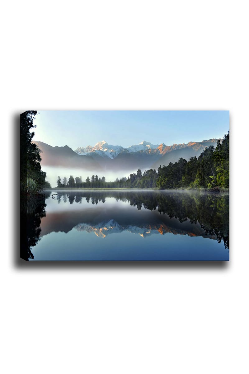 Canvas taulu 70x100 cm - Peilikuva majesteettisista vuorista heijastuen tyynessä järvessä rehevän metsän ympäröimänä, Sininen / Vihreä / Valkoinen