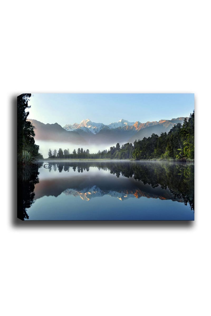 Canvas taulu 70x100 cm - Peilikuva majesteettisista vuorista heijastuen tyynessä järvessä rehevän metsän ympäröimänä, Sininen / Vihreä / Valkoinen