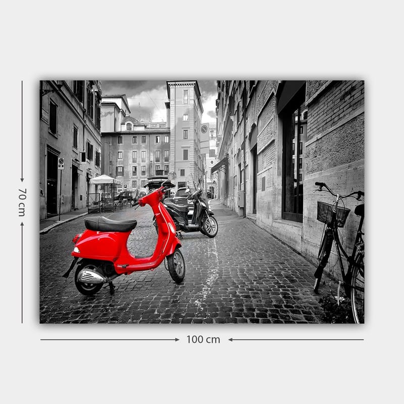 Canvas taulu 70x100 cm - Punainen skootteri seisoo mustavalkoisessa kaupunkiympäristössä mukulakivikatujen ja rakennusten keskellä - Punainen / Musta / Harmaa - Sisustustuotteet - Taulu & taide - Canvas-taulu