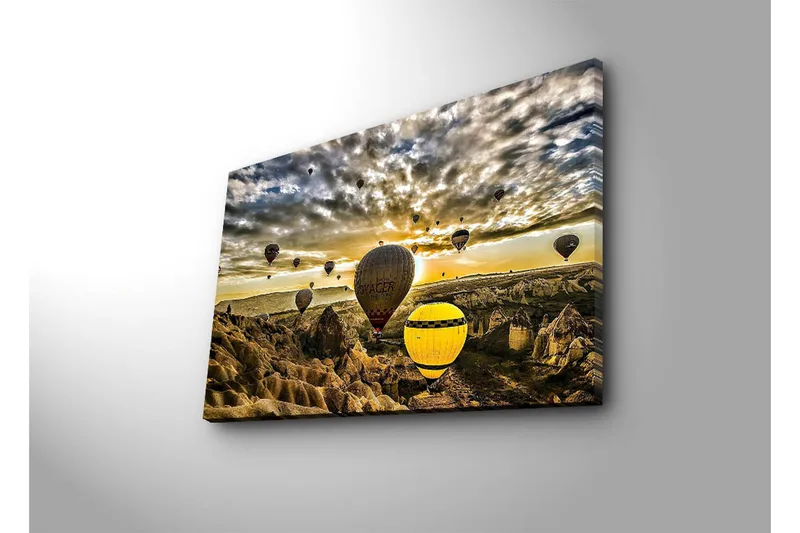 Canvas-taulu 70x45 cm - Useita värikkäitä kuumailmapalloja leijuu dramaattisen maiseman yllä auringonlaskun aikaan - Keltainen / Harmaa / Ruskea - Sisustustuotteet - Taulu & taide - Canvas-taulu