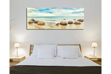 Canvas-taulu 80x30 cm - Pyöreitä kiviä rannalla, taustalla meri ja taivas - Sininen / Beige / Harmaa - Sisustustuotteet - Taulu & taide - Canvas-taulu