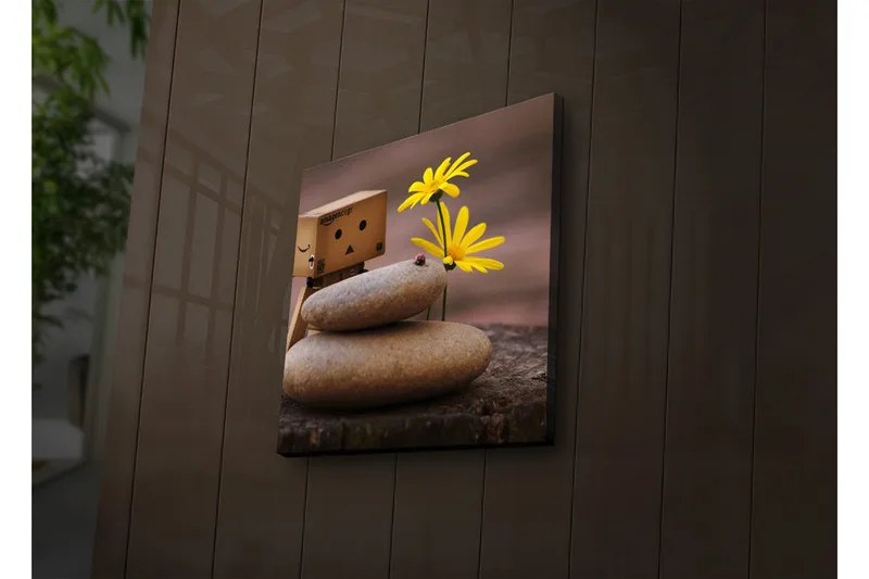 Canvas-taulu LED-valaistuksella 28x28 cm - Lelumainen hahmo keltaisilla kukilla ja kivillä, Keltainen / Harmaa / Ruskea