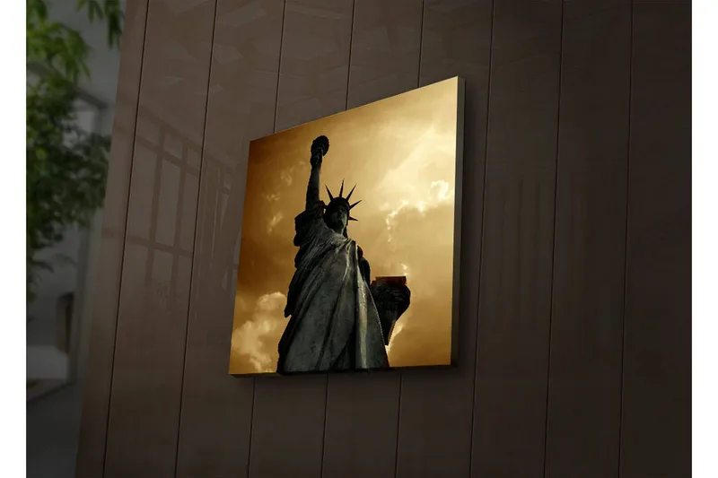 Canvas-taulu LED-valaistuksella 28x28 cm - Vapaudenpatsas majesteettisessa asennossa dramaattista taivasta vasten, Kulta / Harmaa / Musta