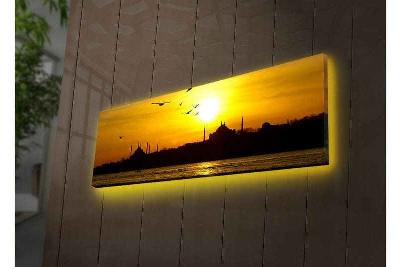 Canvas-taulu LED-valaistuksella 30x90 cm - Auringonlasku kaupungin siluetin yllä lennossa olevien lintujen kanssa, Kulta / Musta / Oranssi