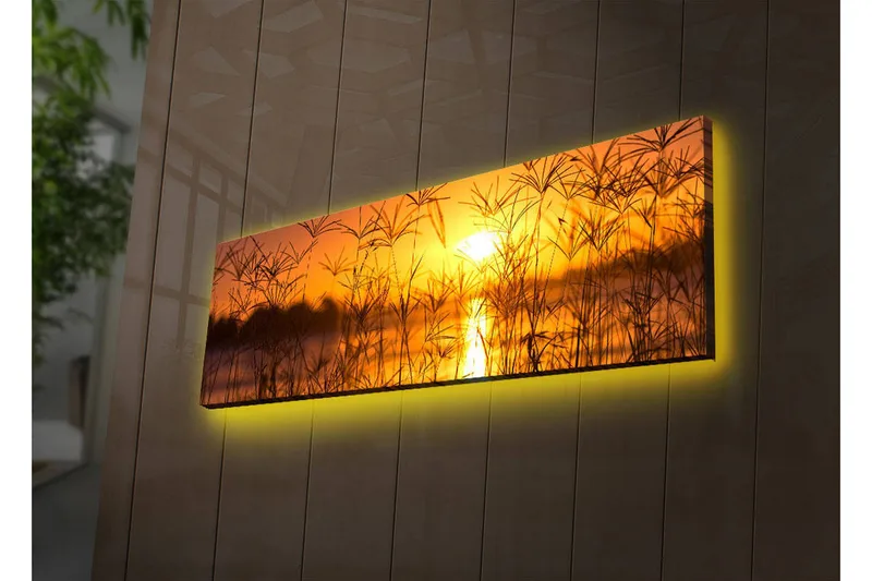 Canvas-taulu LED-valaistuksella 30x90 cm - Auringonlasku peilimäisen järven yllä, etualalla ruohoa, Oranssi / Kulta / Musta