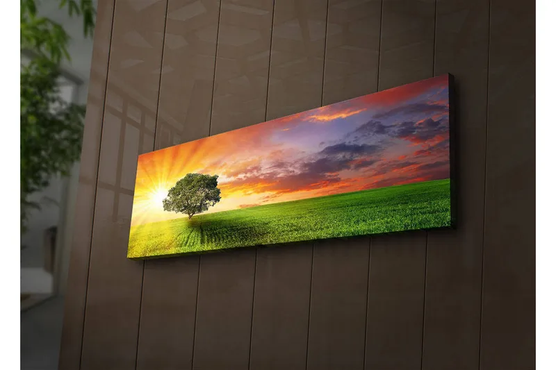 Canvas-taulu LED-valaistuksella 30x90 cm - Auringonnousu vihreän niityn yllä yksinäisen puun kanssa, Vihreä / Oranssi / Sininen