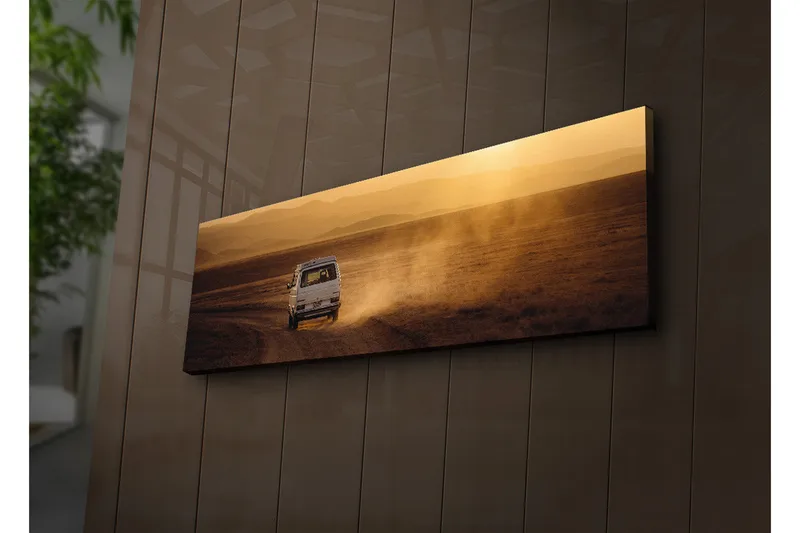Canvas-taulu LED-valaistuksella 30x90 cm - Värikäs maisemakuva, jossa auto ajaa soratiellä, Kulta / Ruskea