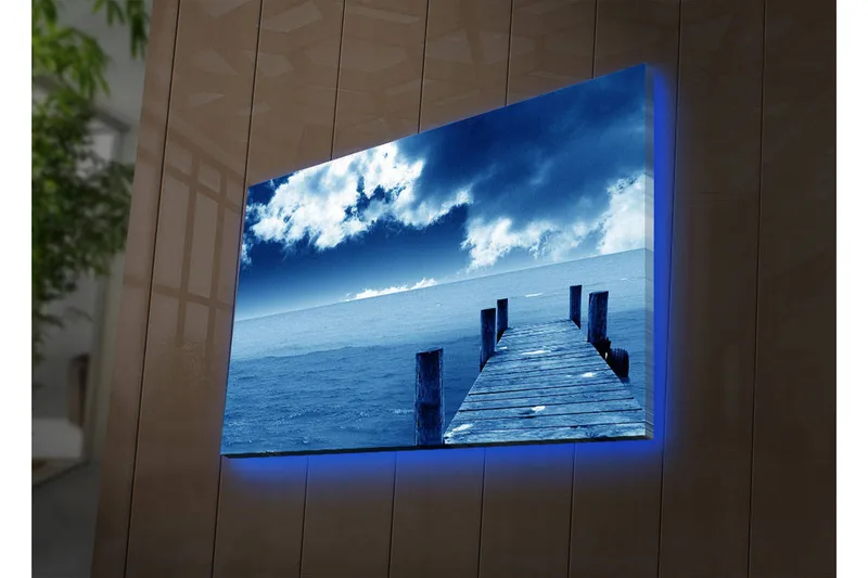 Canvas-taulu LED-valaistuksella 45x70 cm - Asetelma laiturista, joka ulottuu sinisen meren ylle dramaattisen taivaan alla, Sininen / Harmaa / Valkoinen