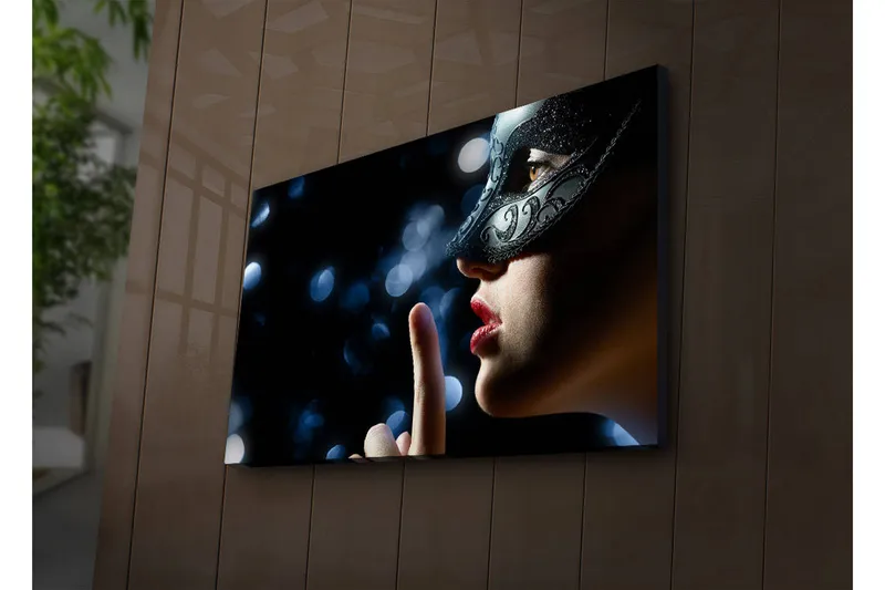 Canvas-taulu LED-valaistuksella 45x70 cm - Salaperäinen nainen naamioineen tekee hiljaisuuden eleen, Musta / Ihonväri / Punainen