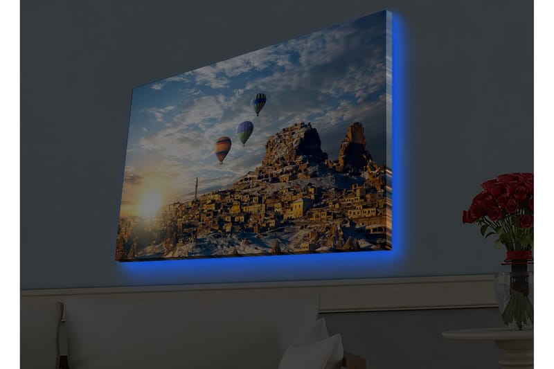 Canvas-taulu LED-valaistuksella - Värikkäät kuumailmapallot leijuvat vuoristoisen maiseman yllä auringonlaskun aikaan, Kulta / Sininen / Oranssi