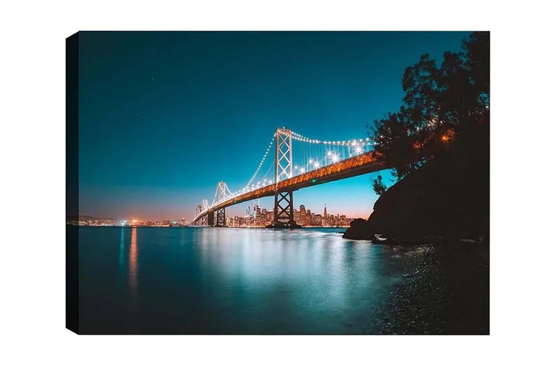 Canvas-taulu - Valaistu silta tyynen veden pinnan yli, taustalla kaupungin siluetti, Sininen / Oranssi / Musta